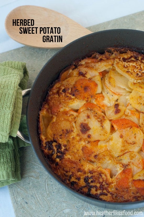 Delicious Herbed Sweet Potato Gratin in a large black skillet next to a wooden spoon.