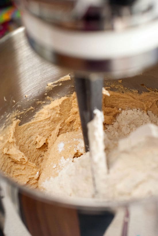 Flour and baking soda with cookie mixture in an electric mixer.