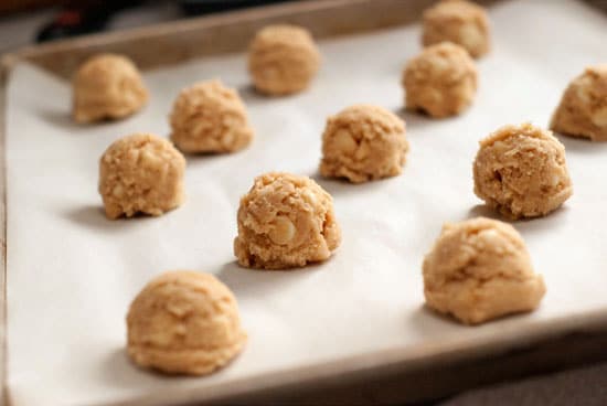 White Chocolate Cookie balls on a parchment lined baking sheet.