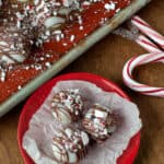 Three simple Oreo Cookie Balls with peppermint bark on a small red plate lined with parchment paper,