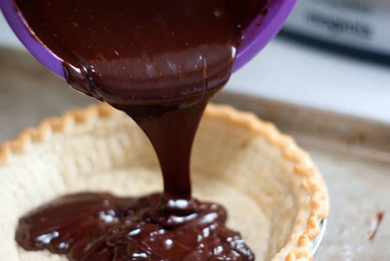 Pouring chocolate ganache into pre-made pie crust.