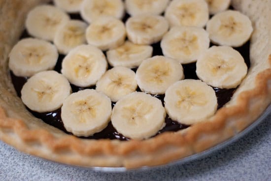 Sliced bananas and ganache in a pie crust.