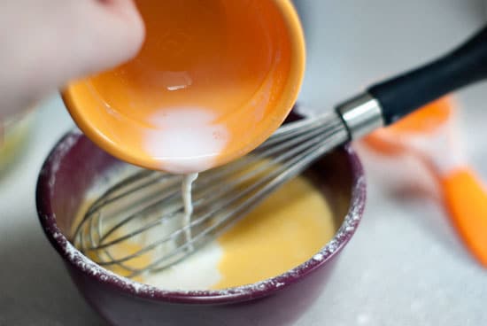 Pouring hot milk into egg mixture.