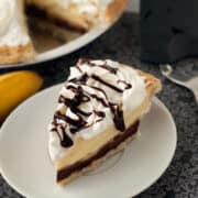 Easy Banana Cream Pie drizzled with chocolate and whipped cream in a small white plate.