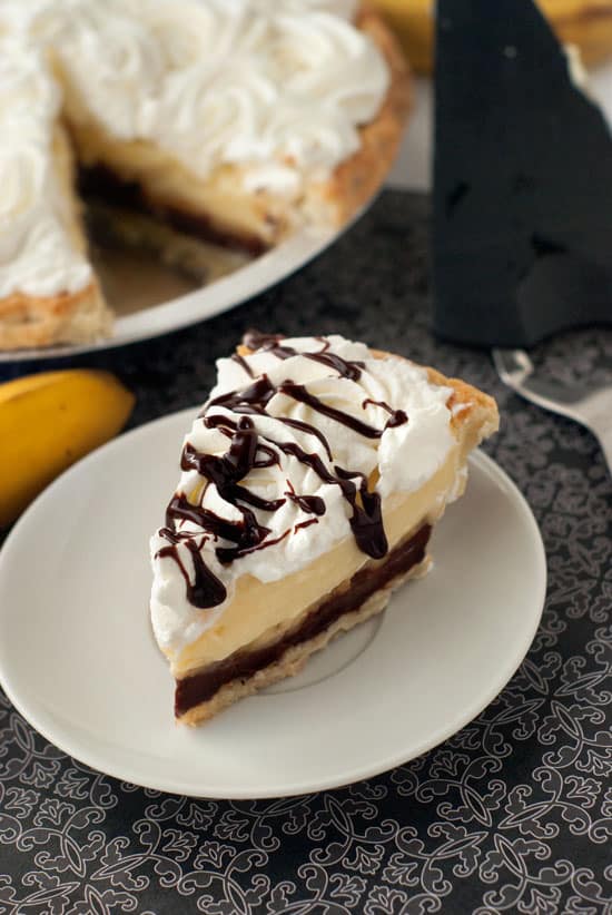Black Bottom Banana Cream Pie with whipped cream and chocolate on a small white plate.