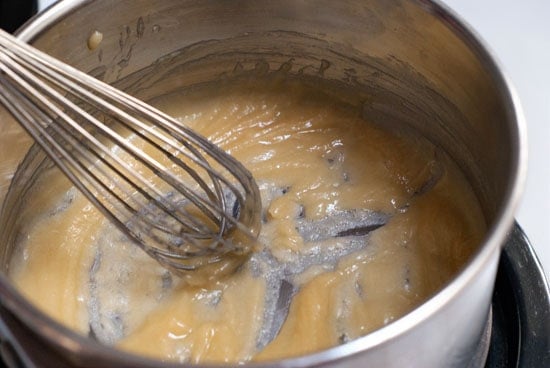 Whisking together eggs and flour in a silver mixing bowl.