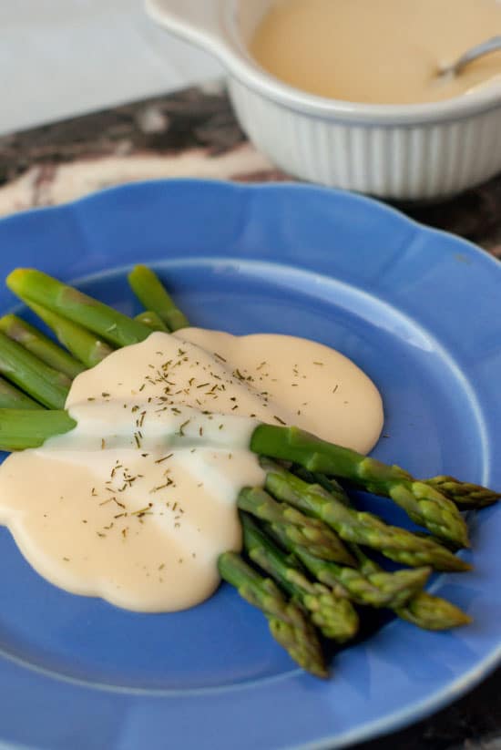 Asparagus smothered in Easy Cheese Sauce on a large blue plate.