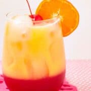 Non alcoholic drink in a drinking glass with fresh oranges and cherries.