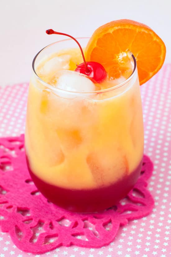 Hugs on the Beach drink garnished with sliced orange and a cherry.