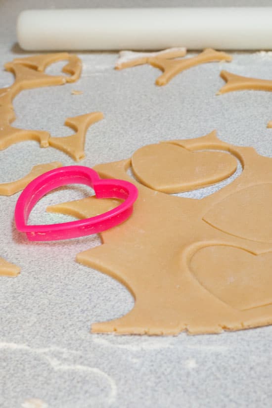 Pink heart shaped cookie cutter on sour cream sugar cookie dough.