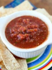 Fast Salsa recipe in a small white bowl surrounded by mexican tortilla chips.