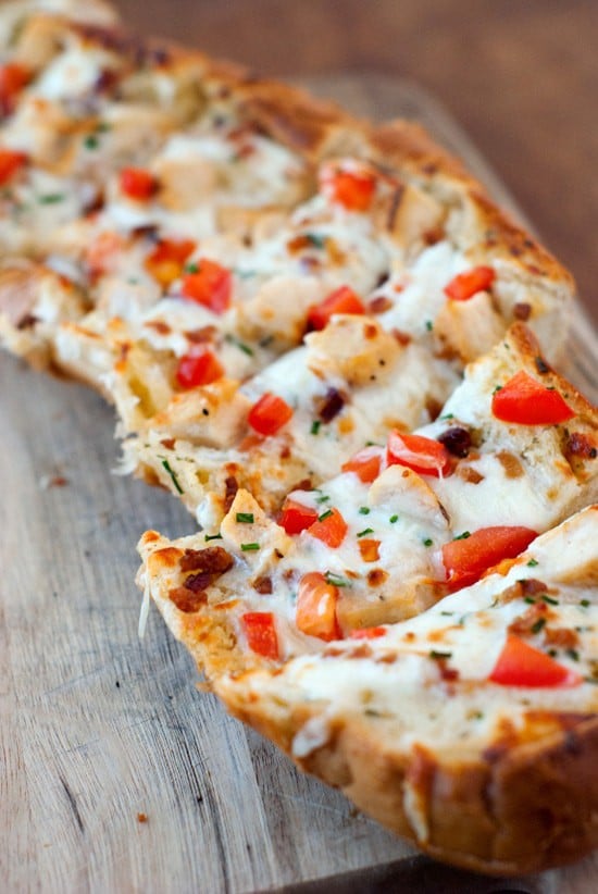Split apart Garlic Bread Pizza with fresh tomatoes, mozzarella on a wooden board.