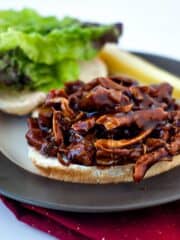 Simple BBQ Chicken Sandwiches on a grey plate on top of a red cloth.
