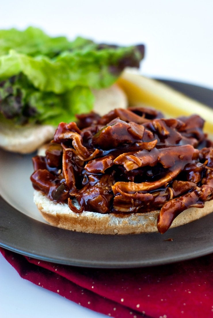 Delicious BBQ Chicken Sandwich on a plate on top of a red tablecloth.