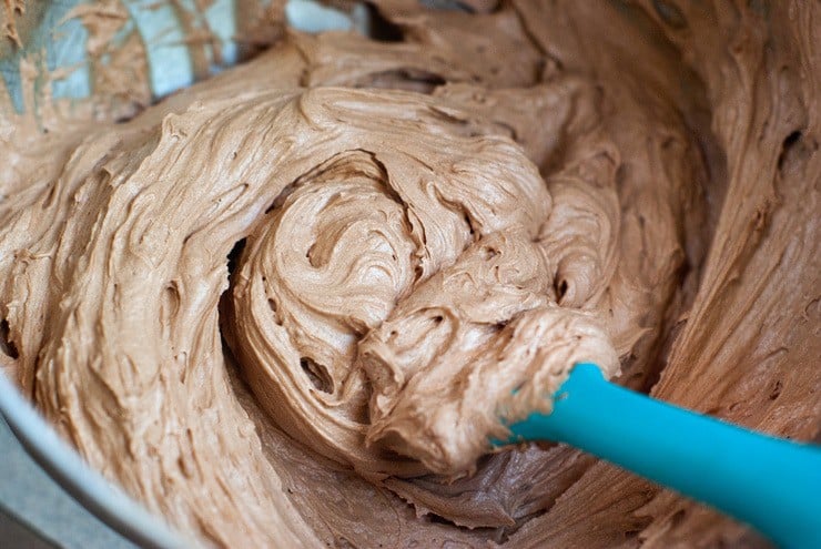 Mixing Perfect Chocolate Frosting in a mixing bowl with a blue spatula.