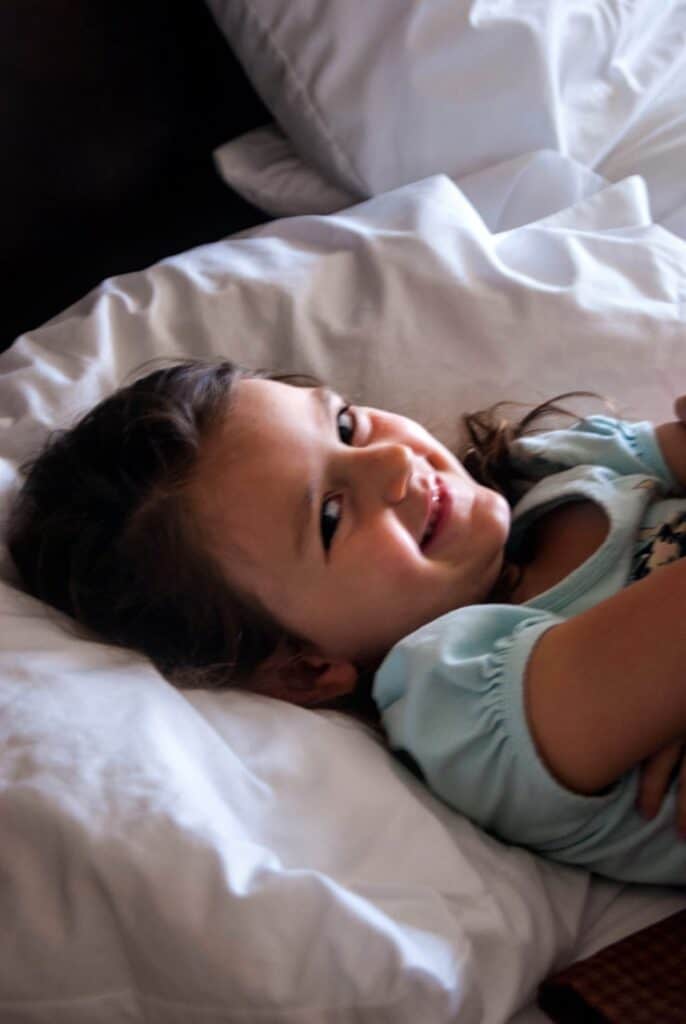 Little girl laying on top of a white pillow.