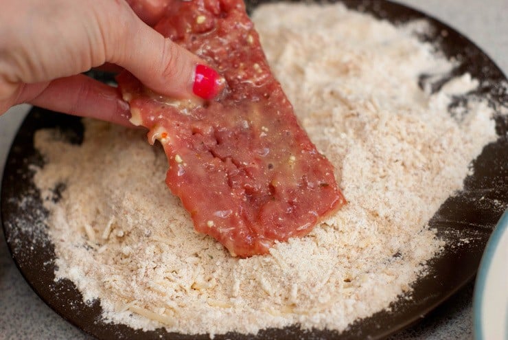 Dipping shredded beef into shredded parmesan.