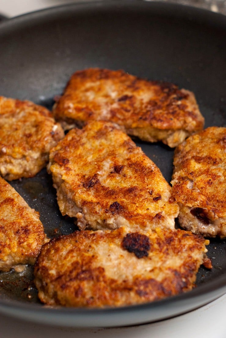 Cooking Beef Parmesan patties in a black skillet.