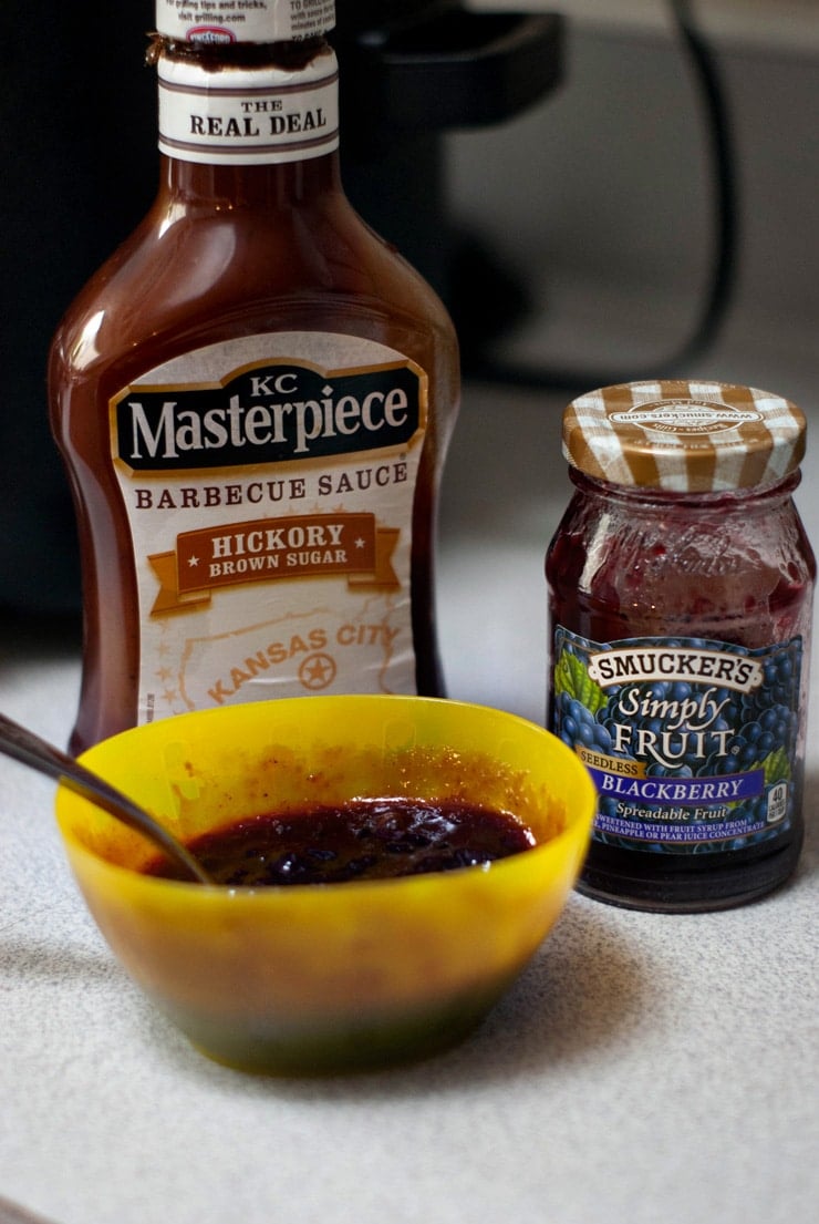 KC Masterpiece BBQ Sauce and Smuckers Blackberry Jam on a white table.