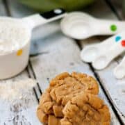 Easy Peanut Butter Cookies recipe on a wooden table next to measuring spoons.