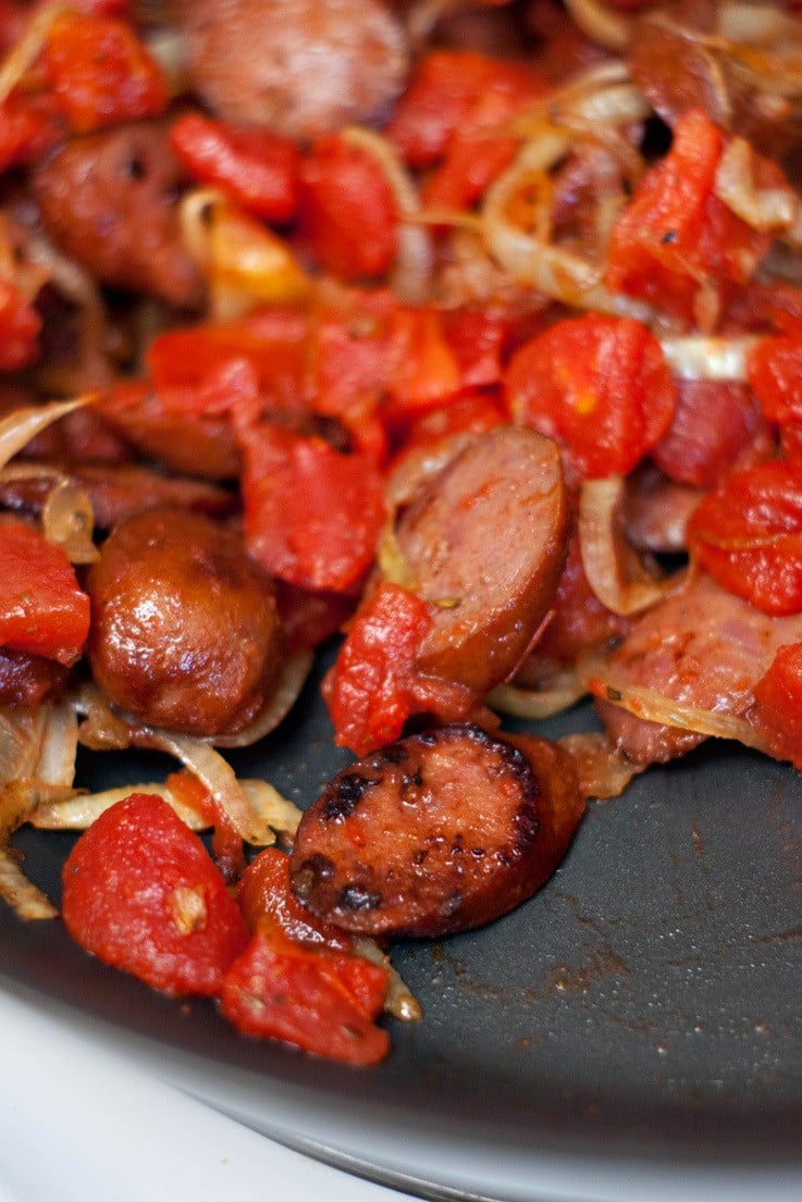 Cooked Sausage and Caramelized Onions in a skillet.