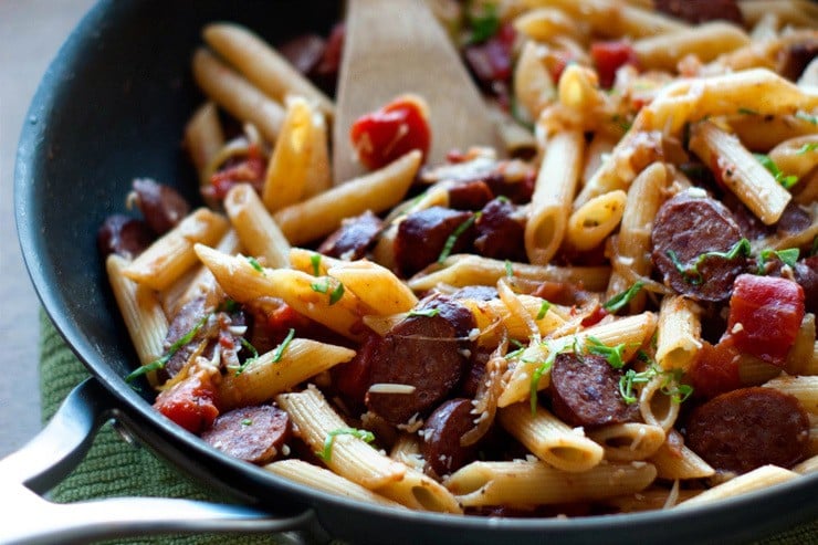 Delicious Penne With Smoked Sausage and Caramelized Onions in a black skillet.