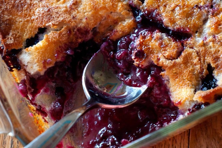 Getting a scoop of Easy Boysenberry Cobbler with a silver spoon.