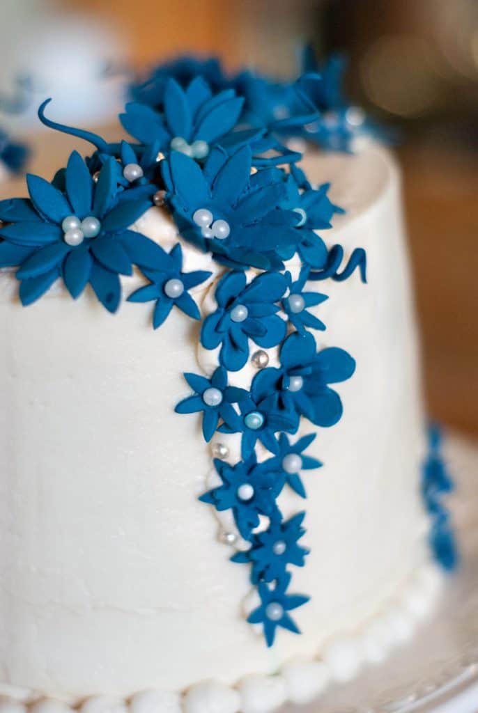 Easy cake with white frosting and decorative blue flowers.