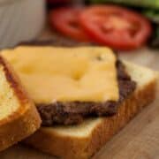 Texas Toast Griddle Burger patty on buttered bread on a wooden board.