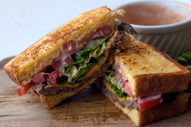 Texas Toast Griddle Burgers sliced in half on a wooden board.