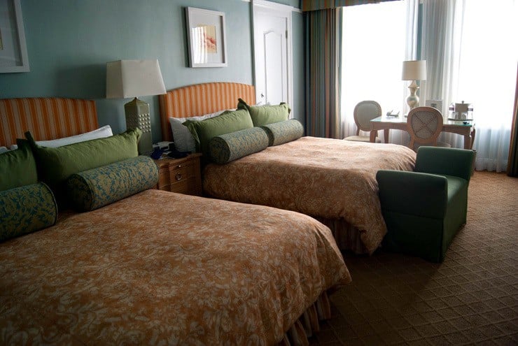 Two beds with green pillows and orange bedding.