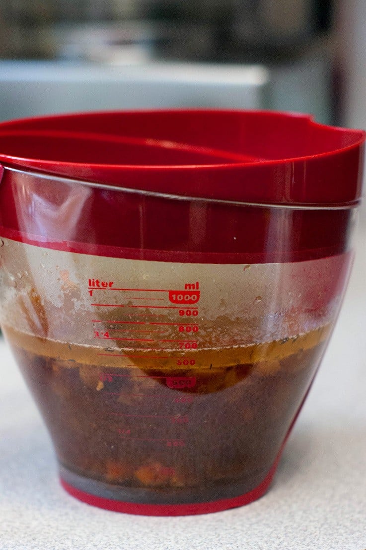 Slow Cooker Pot Roast Gravy on a measuring cup with a red lid.