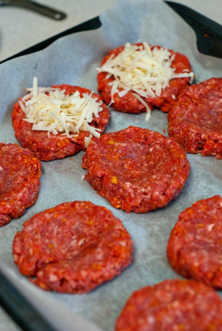 Shredded Pepper Jack cheese on burger meat patties.