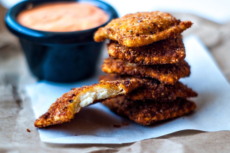 Crispy Ravioli with Roasted Red Pepper Sauce on white parchment paper.