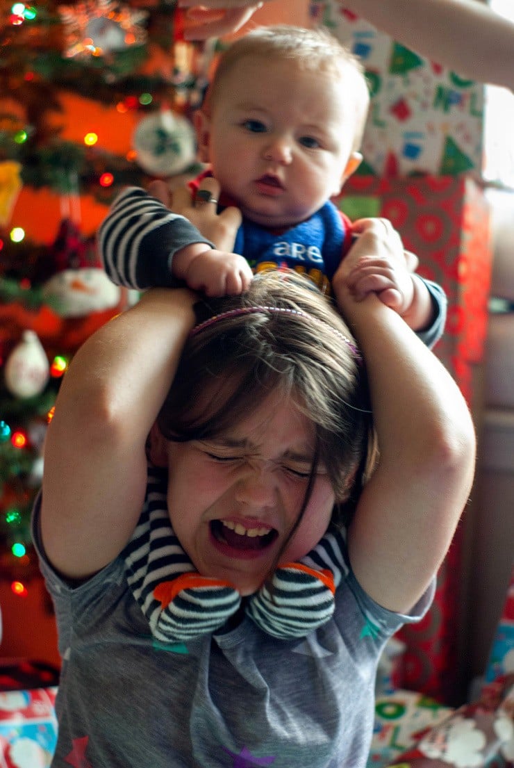 Baby on little girls shoulders on Christmas.