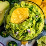 Glass bowl of guacamole with chip inside