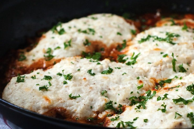 Four chicken breasts topped with ricotta cheese and herbs