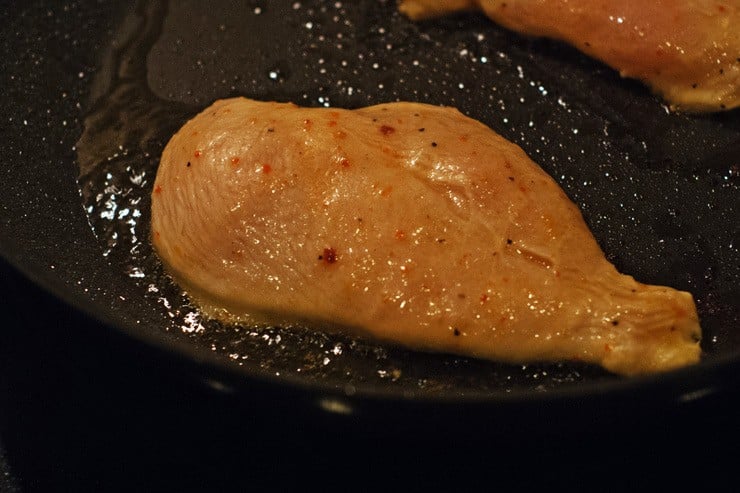 Chicken breast being cooked in a pan
