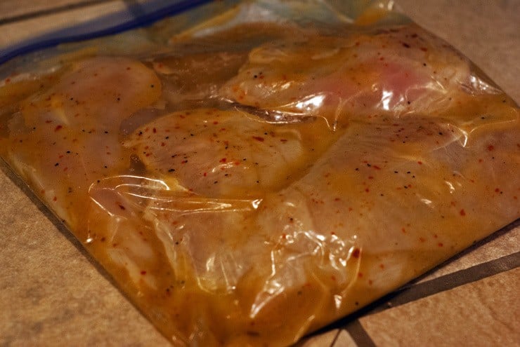 Raw chicken breasts marinading in a ziplock bag.