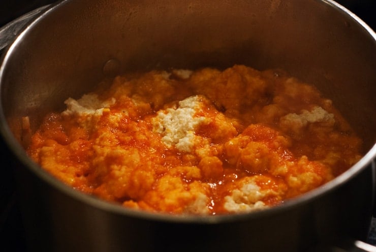 dumplings being cooked in tomato soup