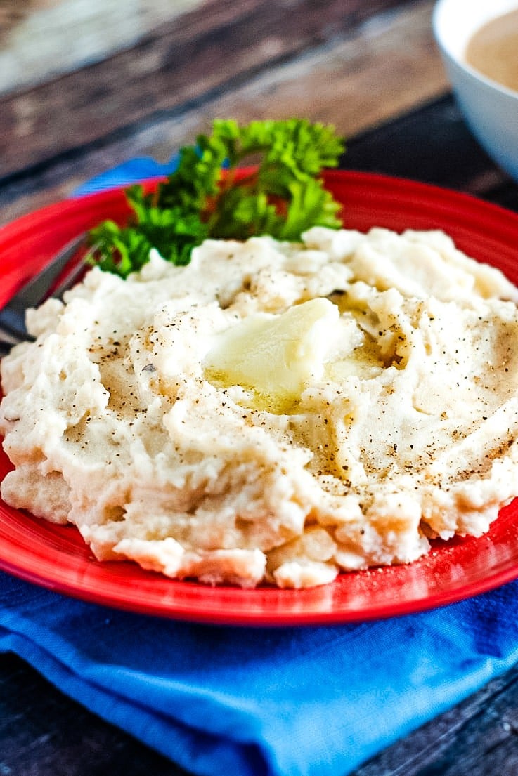 Slow Cooker Mashed Potatoes on a red plate with butter