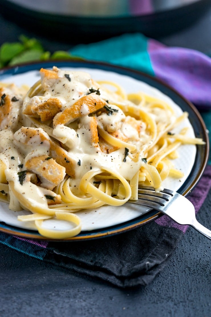 Alfredo sauce over chicken and pasta on a white plate