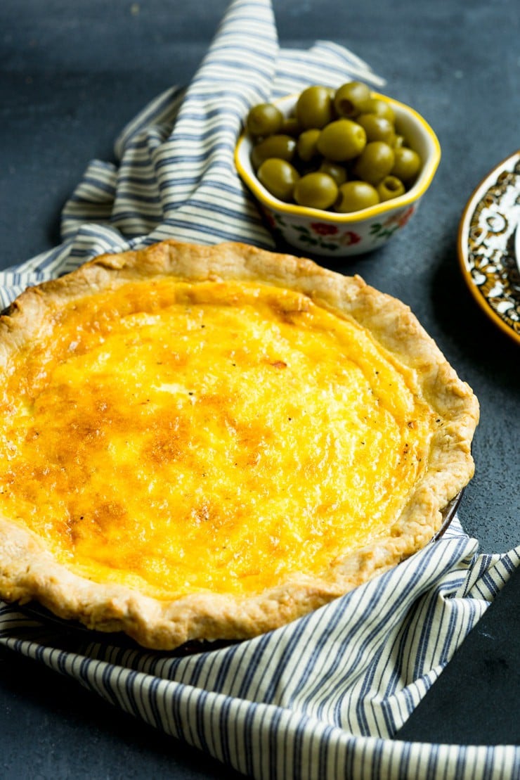 Basic Quiche Recipe in pie pan with a bowl of olives