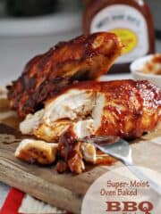 BBQ chicken cut on a cutting board with a bottle of bbq sauce