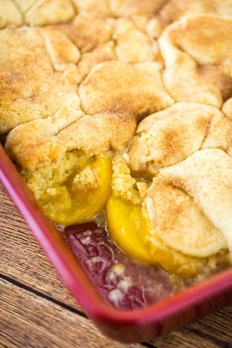 Cobbler made with fresh or frozen peaches and snickerdoodle cooke dough in a red baking dish