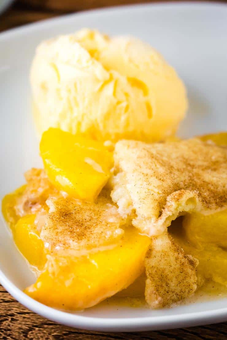 Snickerdoodle Peach Cobble and scoop of vanilla ice cream on white plate
