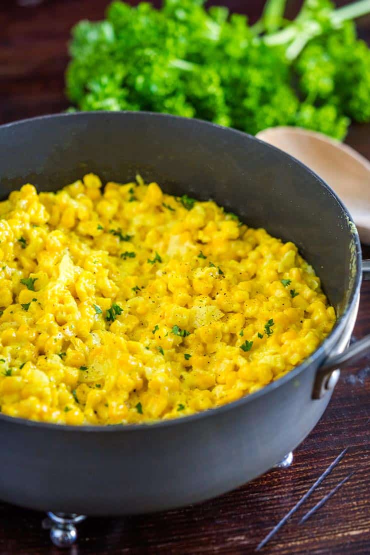 A pan of creamy homemade creamed corn with parsley on top