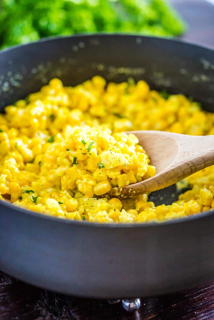 A spoonful of homemade creamed corn in a pan that can be made with fresh or frozen corn