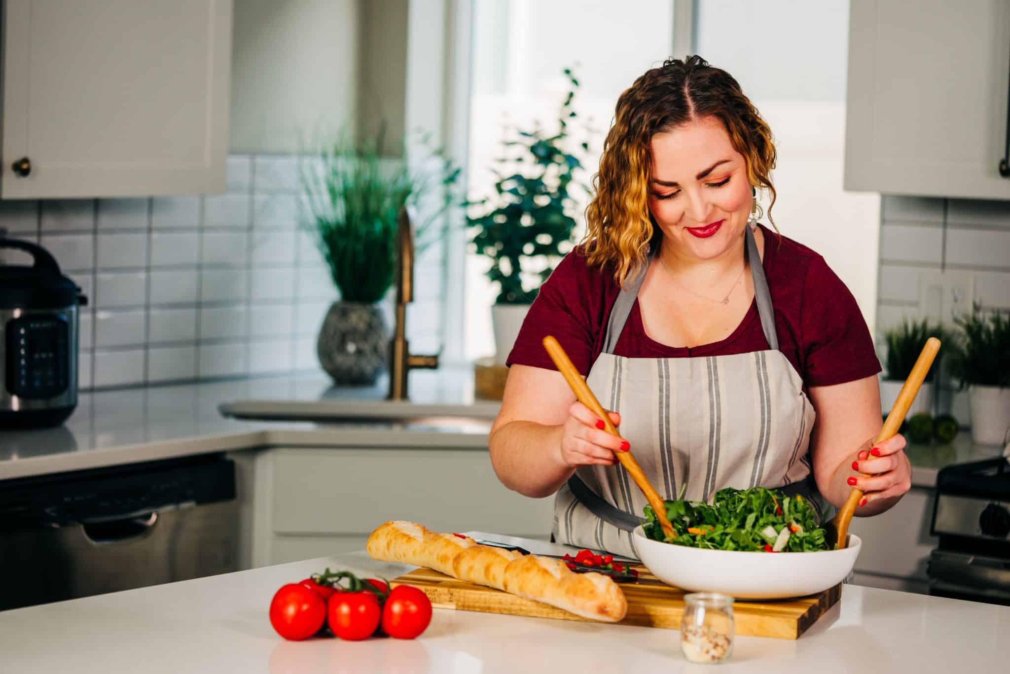 Girl in kitchen tossing a salad