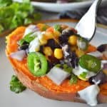 half a sweet potato stuffed with mexican toppings on a white plate